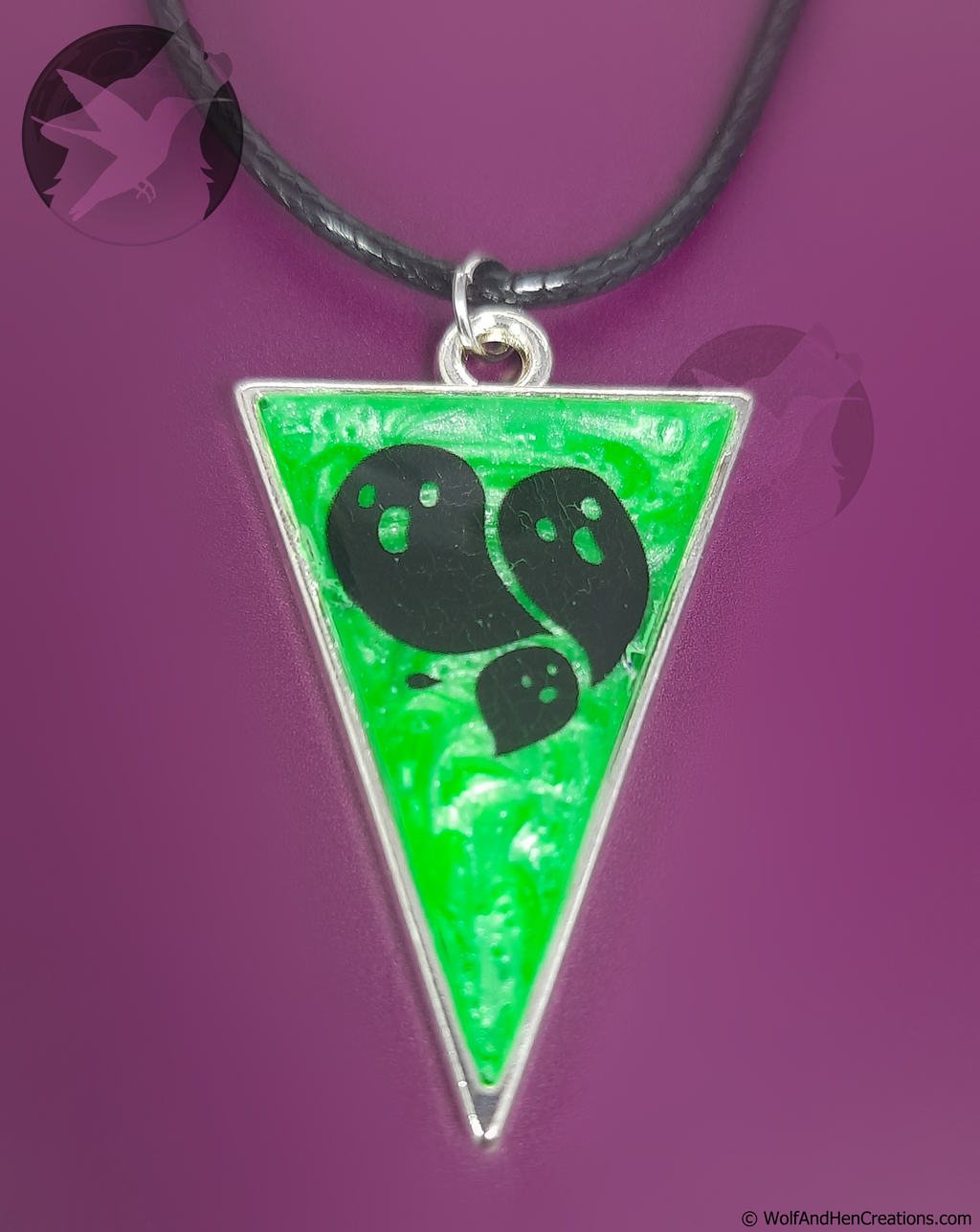 Necklace with a green triangular pendant featuring ghosts on a purple background
