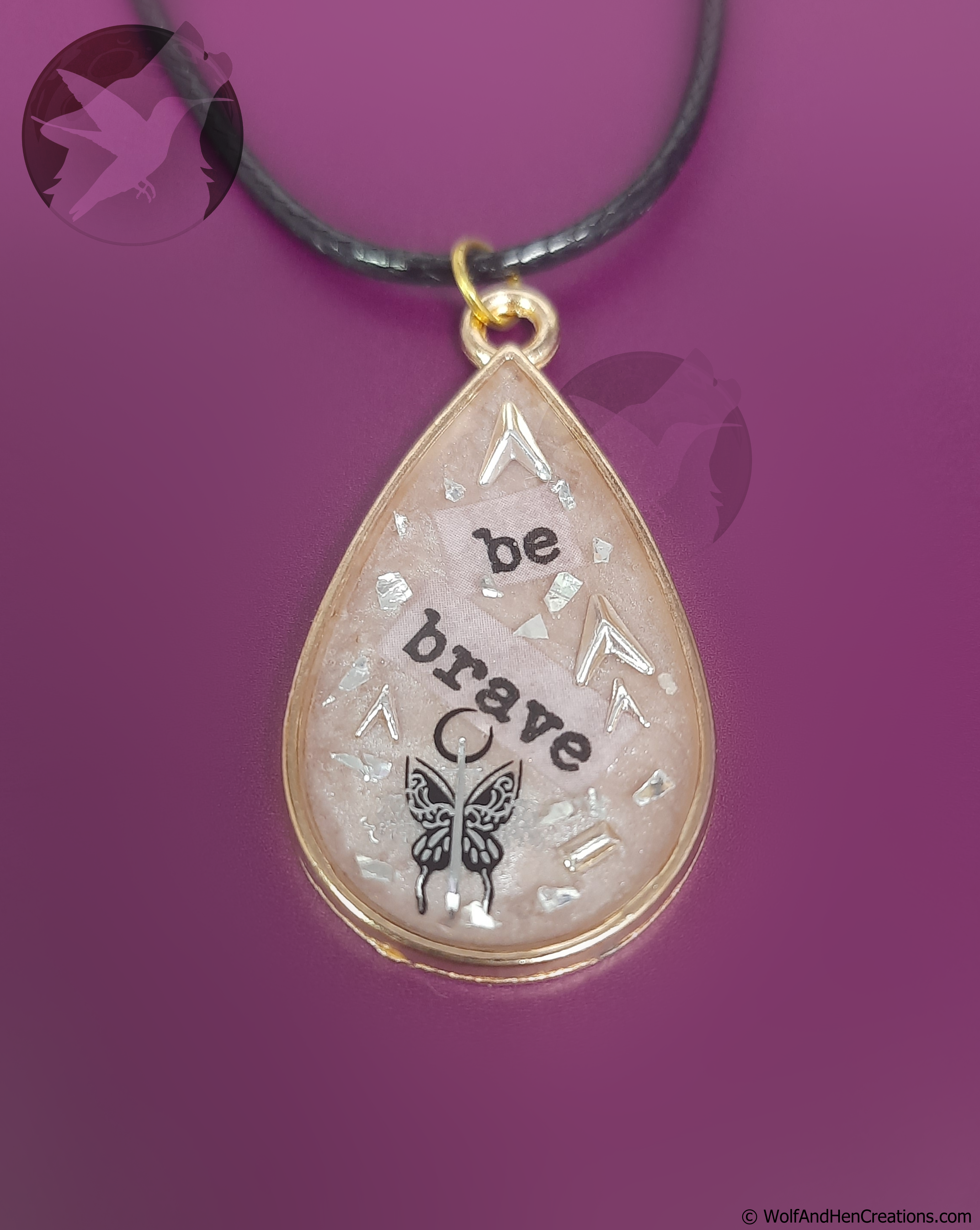 Teardrop shaped pendant with text and a butterfly design on a purple background