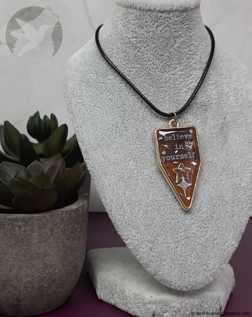 Necklace with a pendant on a mannequin bust next to a potted plant