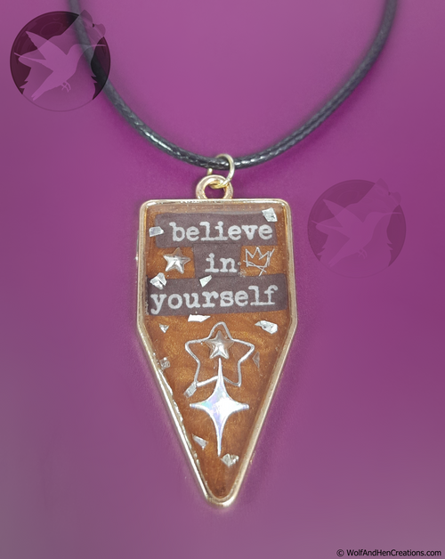 Necklace with a pendant that says 'believe in yourself' on a purple background