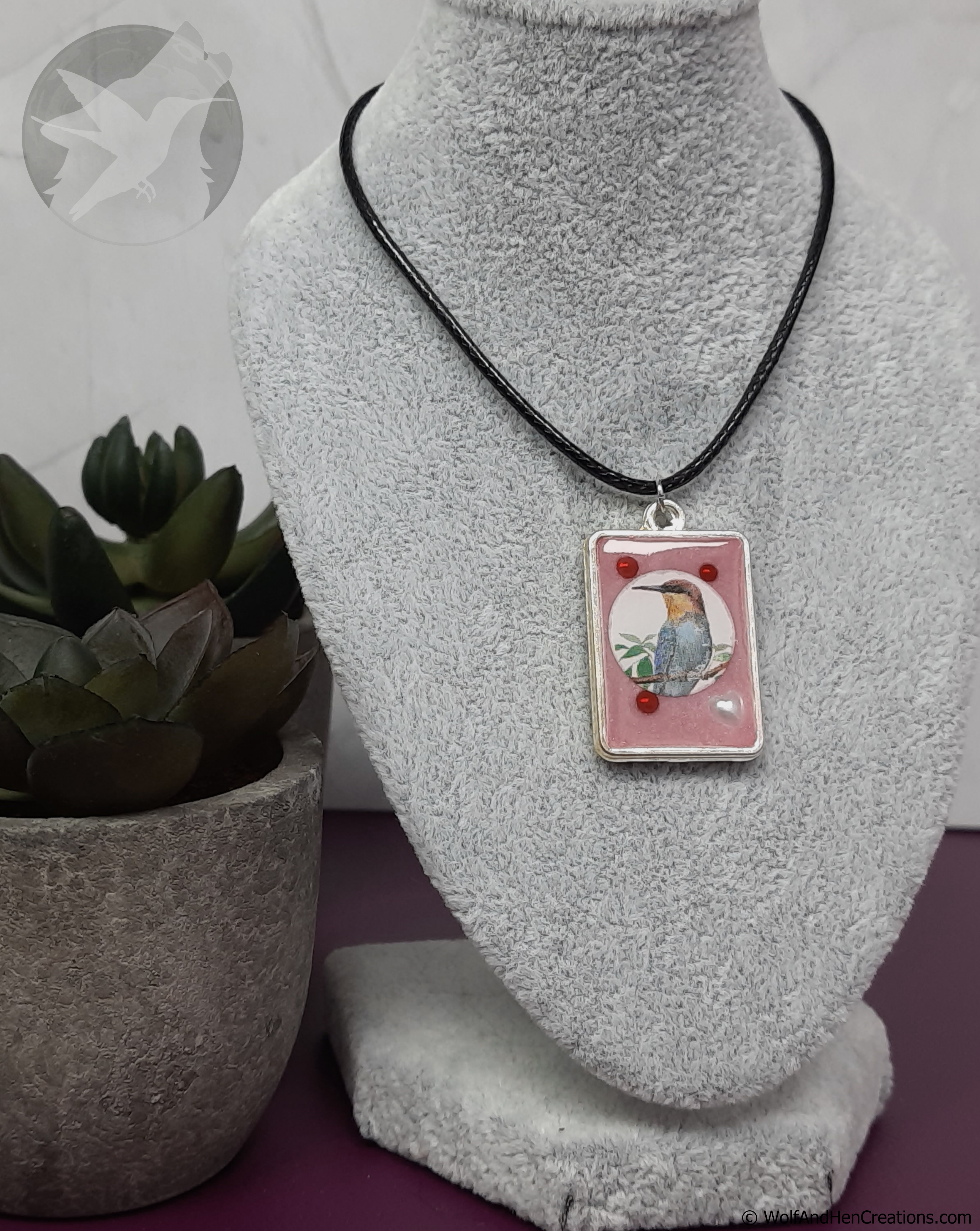 Necklace with a pendant featuring a bird illustration on a gray mannequin bust.