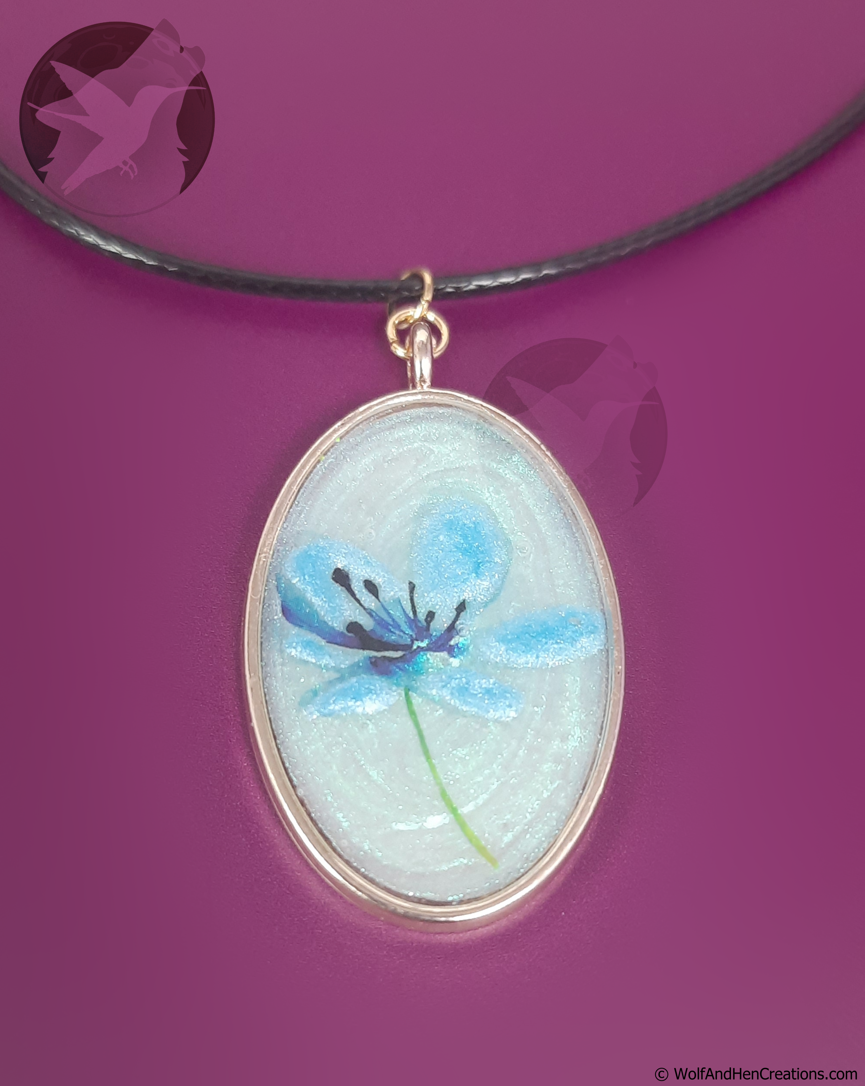 Oval-shaped pendant with blue flower design on a purple background