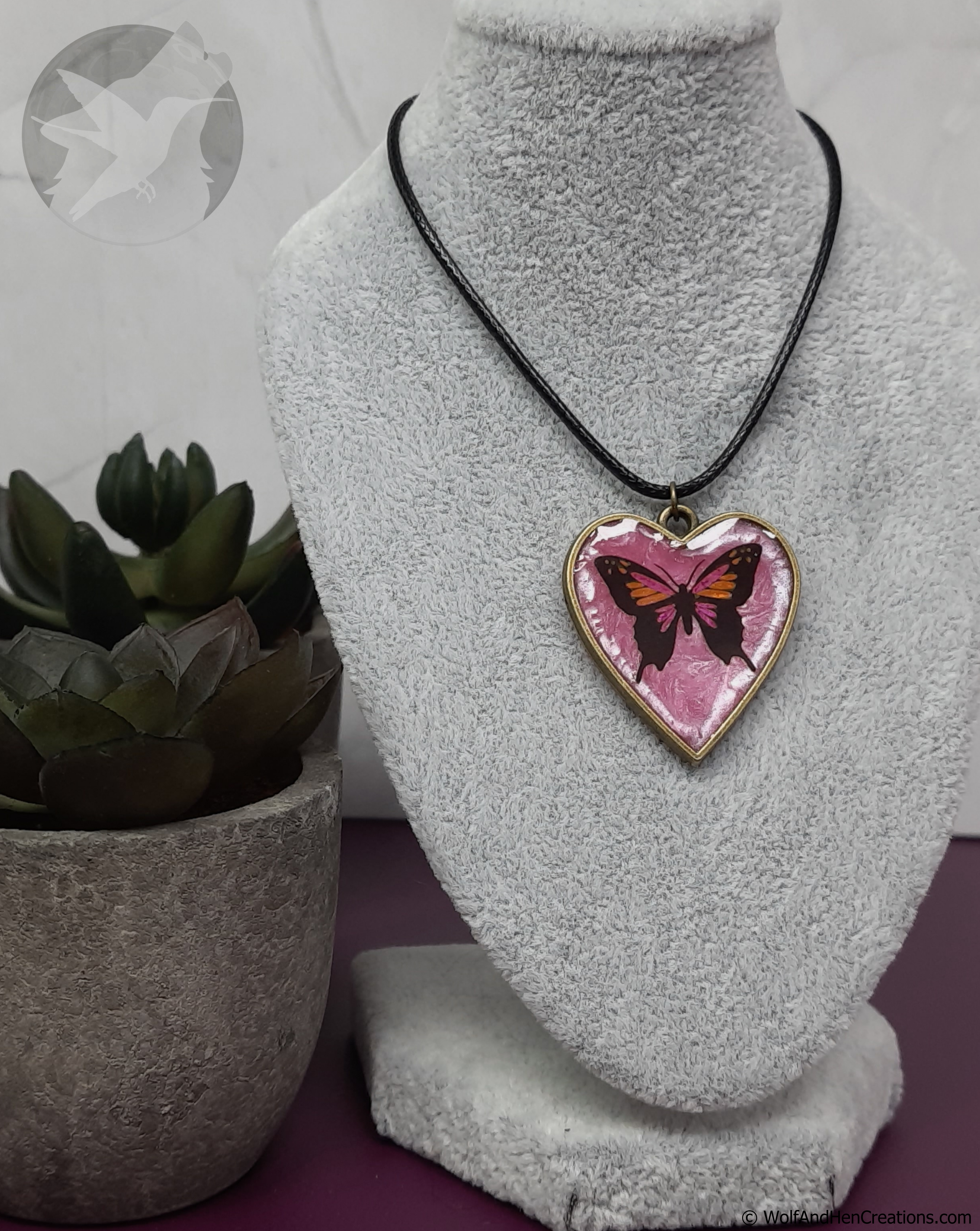 Necklace with a heart-shaped pendant featuring a butterfly design on a gray bust.