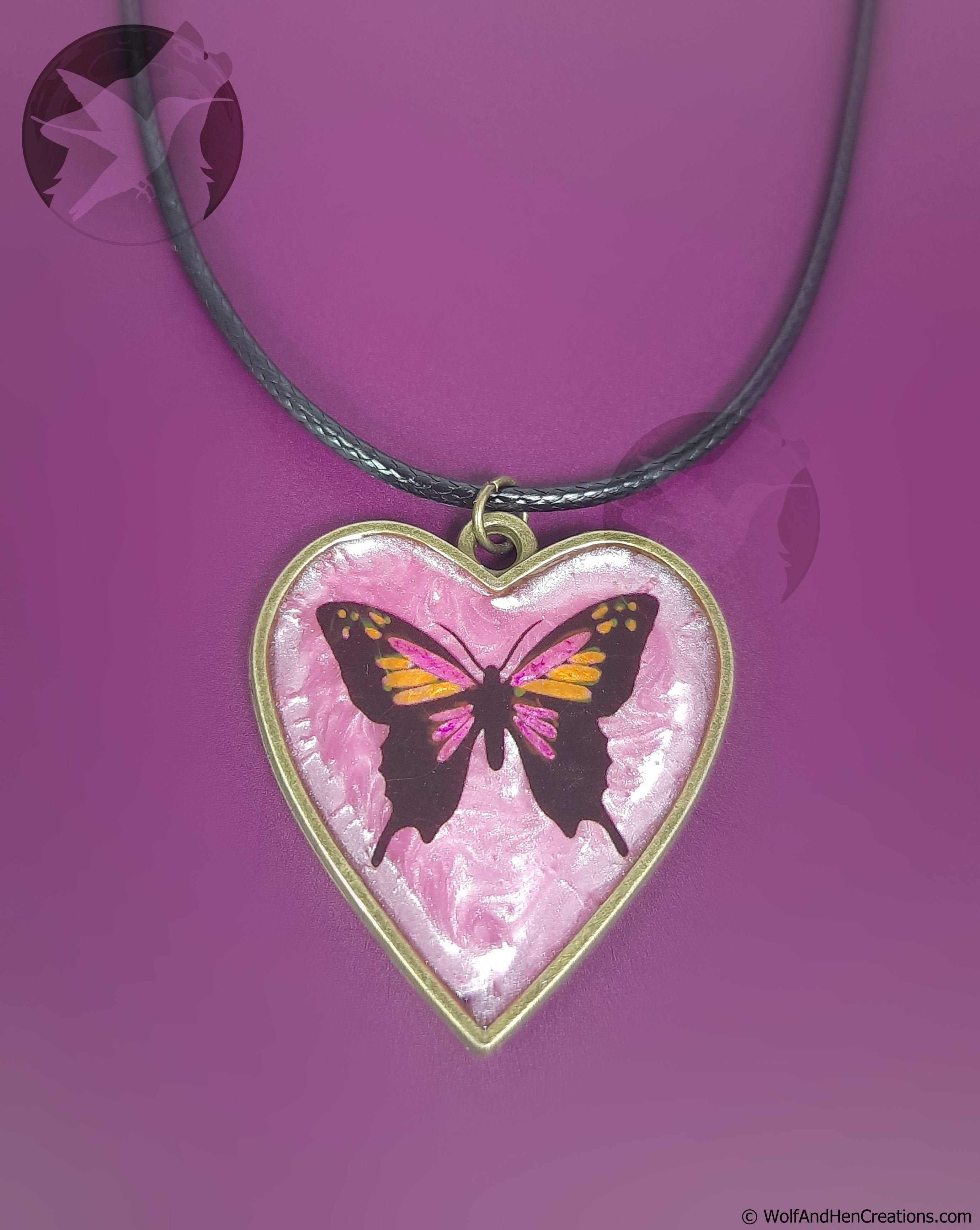 Heart-shaped pendant with butterfly design on a purple background