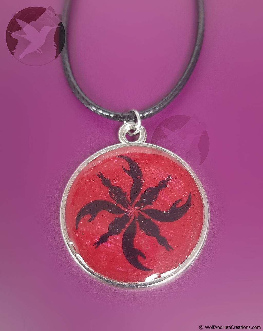 Necklace with a red pendant featuring a black tribal design on a purple background