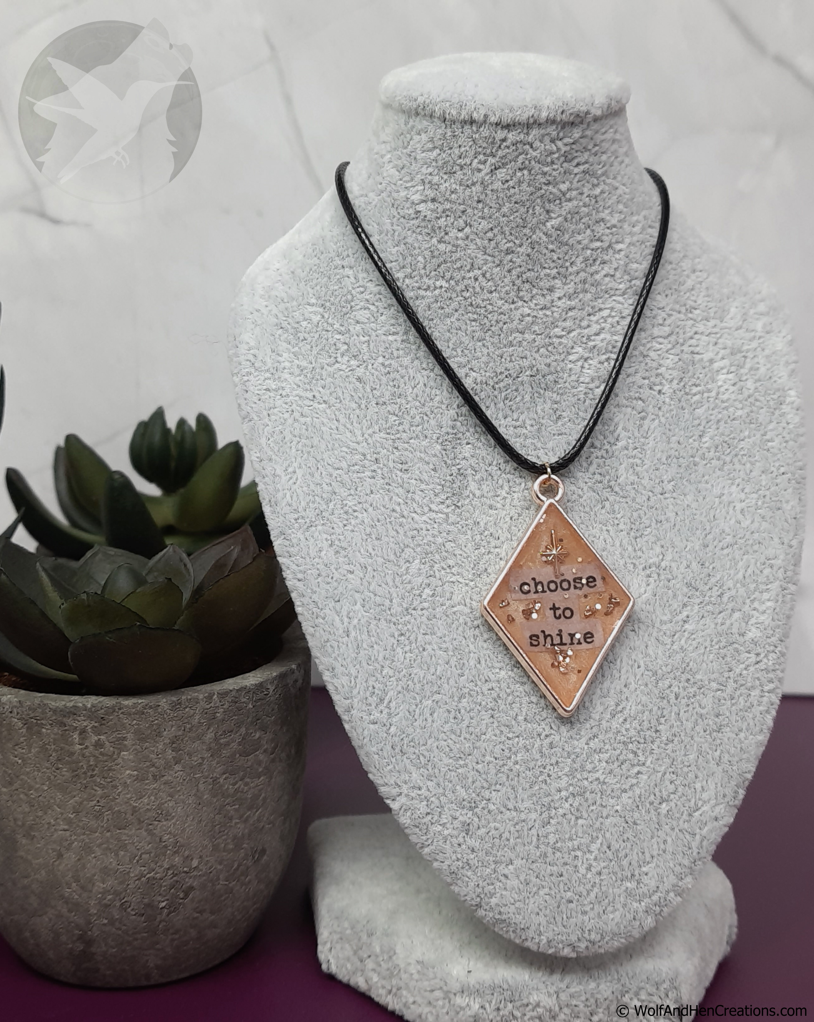 Necklace with a pendant on a mannequin bust next to a potted plant