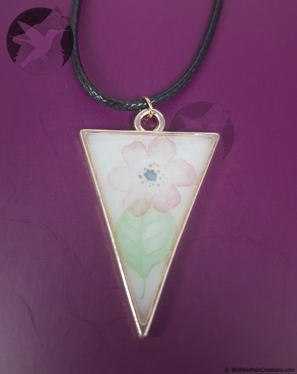 Triangular pendant with floral design on a purple background