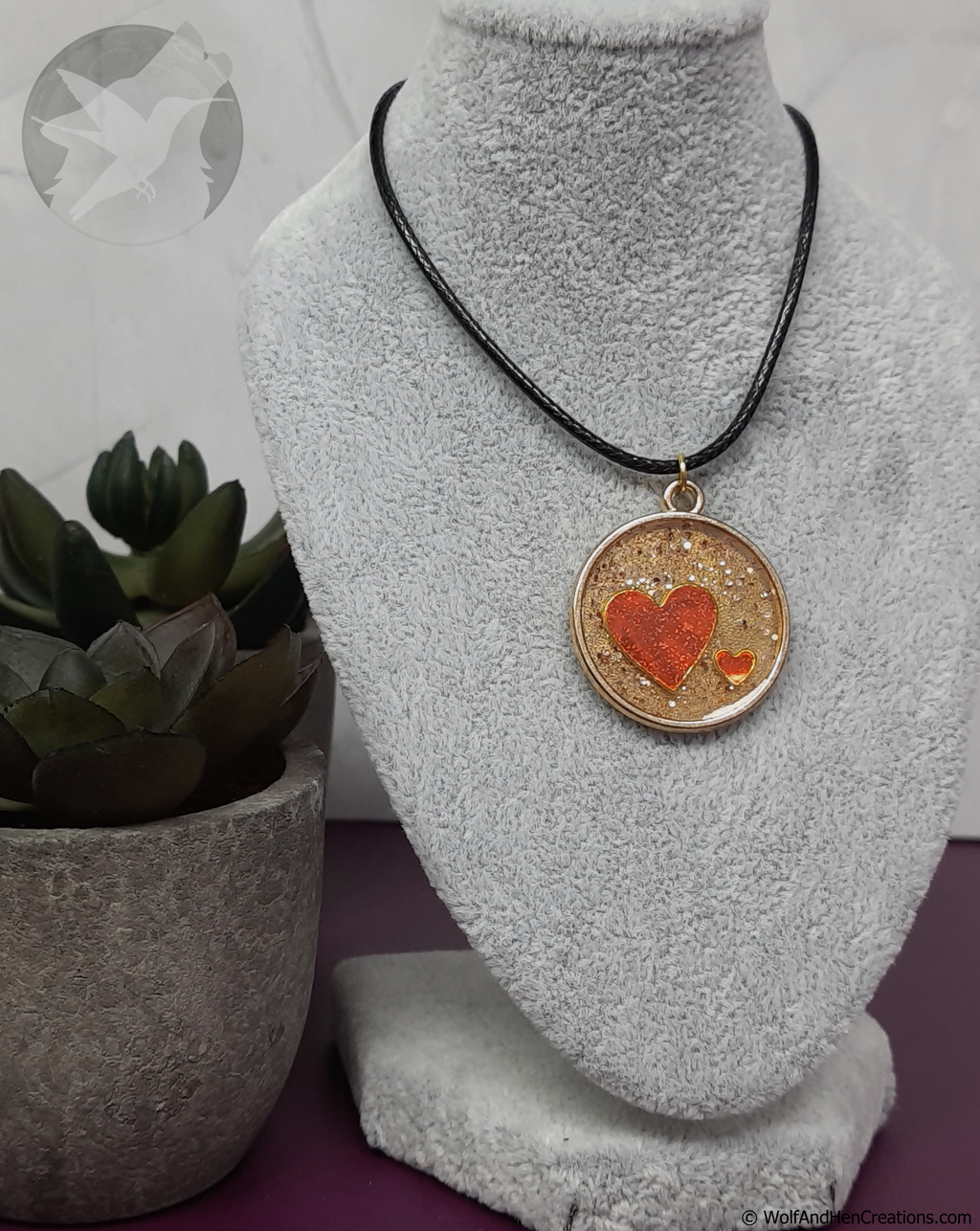 Necklace with a heart pendant on a mannequin bust, next to a potted plant.