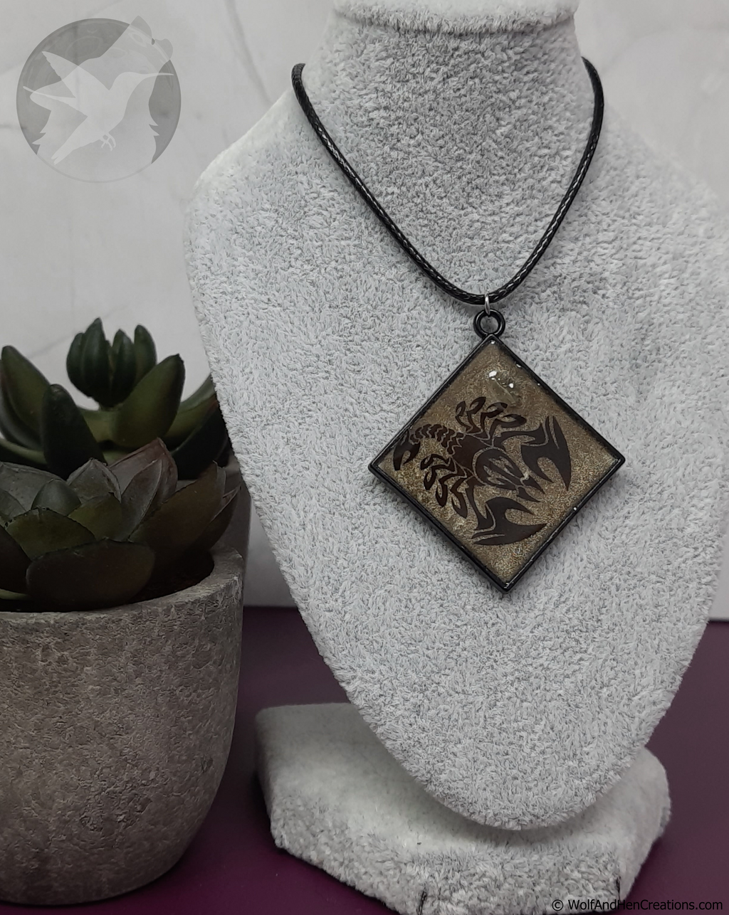 Necklace with a pendant on a mannequin bust next to a potted plant