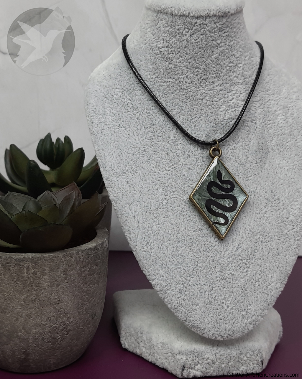 Necklace with a pendant on a mannequin bust next to a potted plant