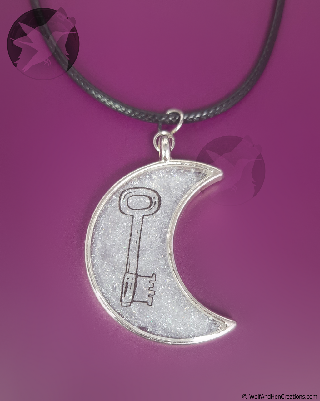 Silver crescent moon pendant with key design on a purple background
