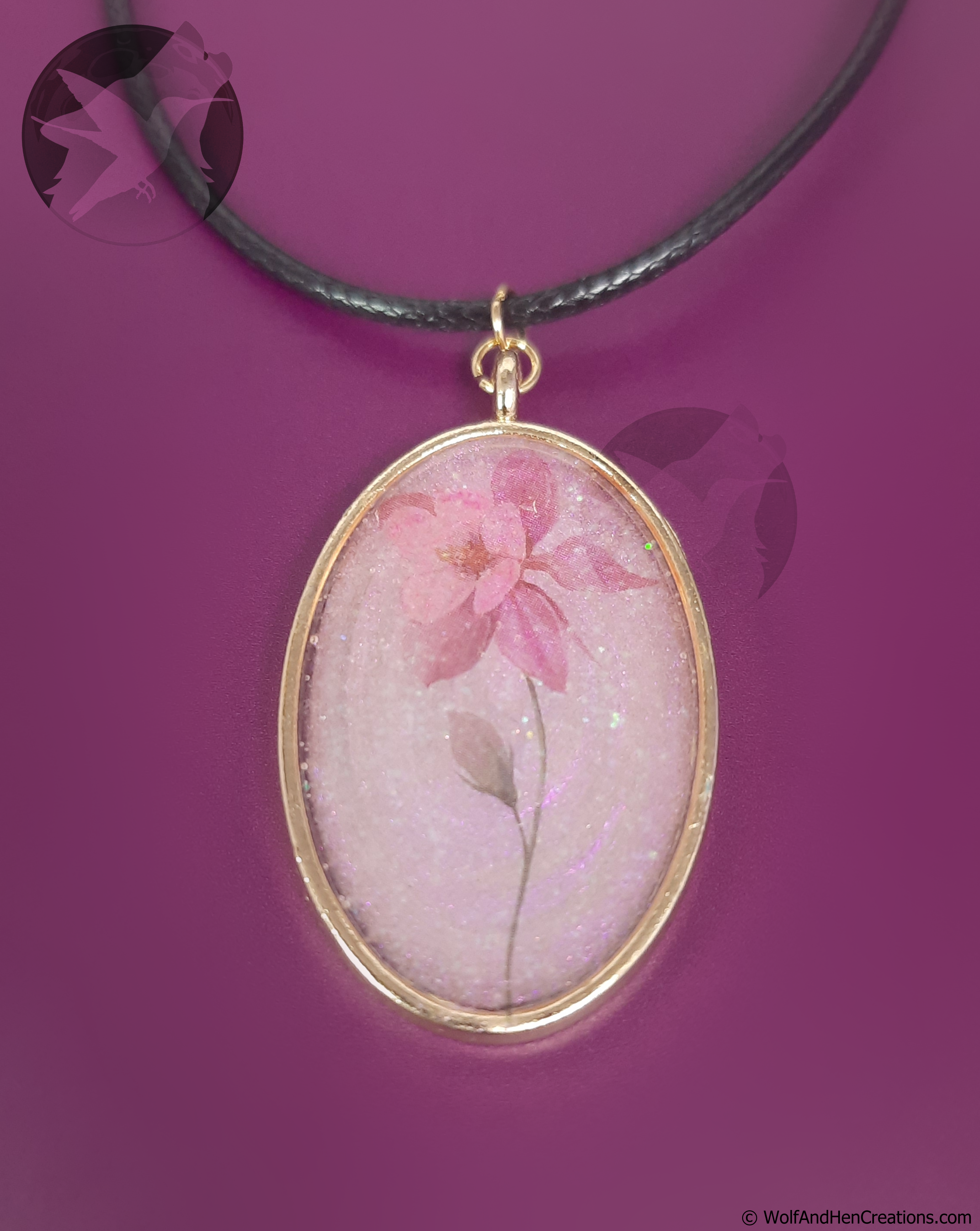 Oval-shaped pendant with pink flower design on a purple background