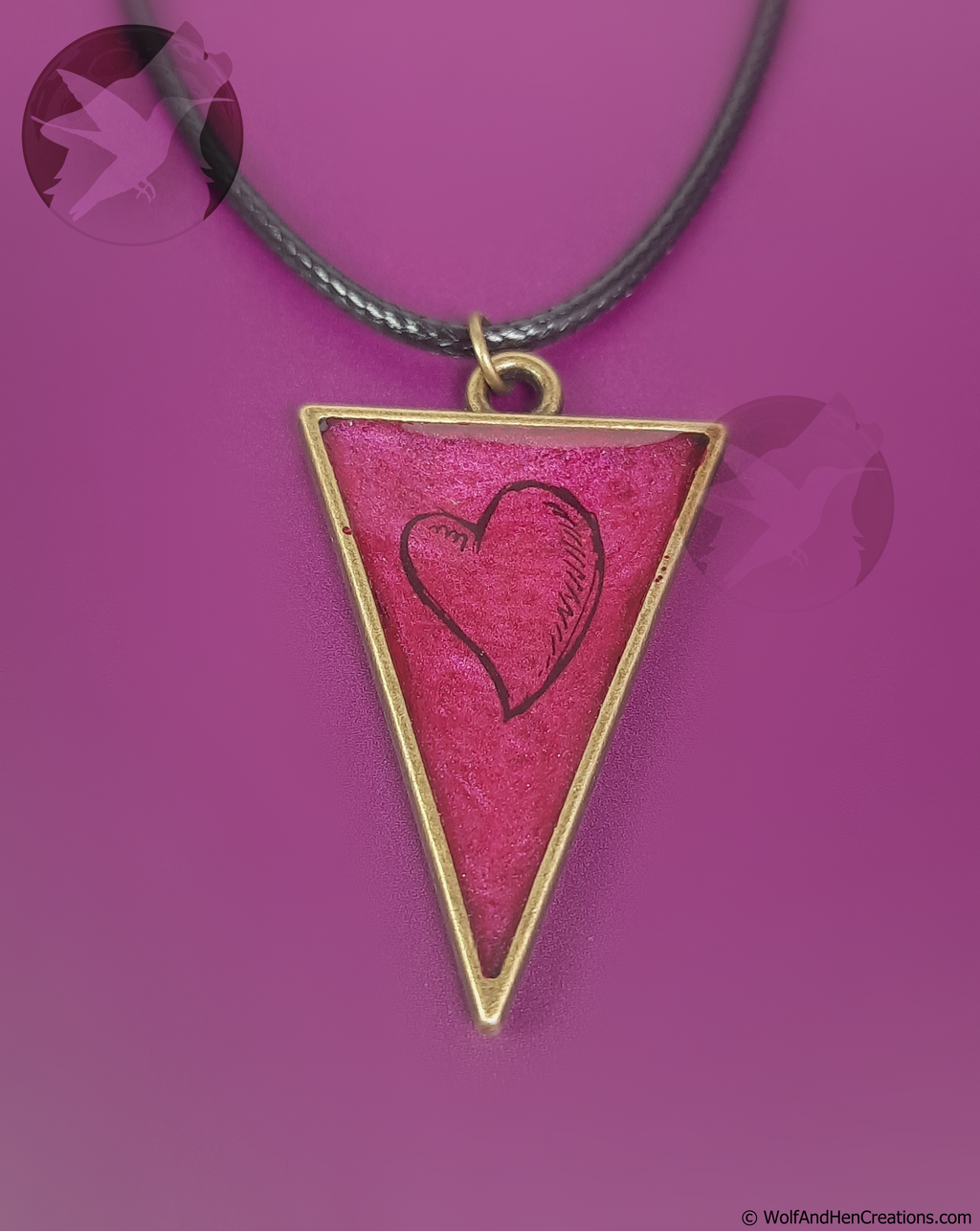 Triangular pendant with red surface and black heart design on a purple background