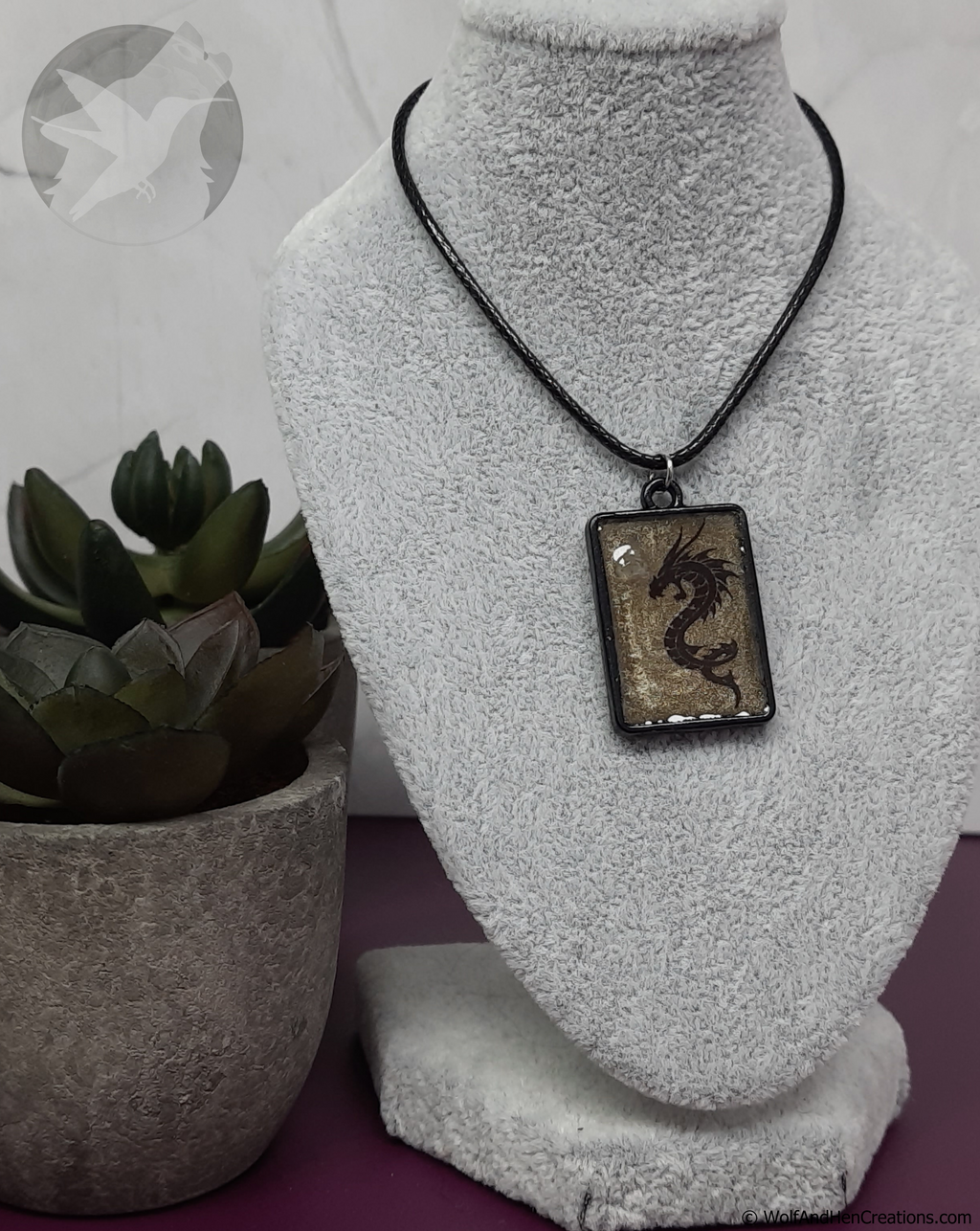 Dragon pendant necklace on a mannequin bust with a plant in the background
