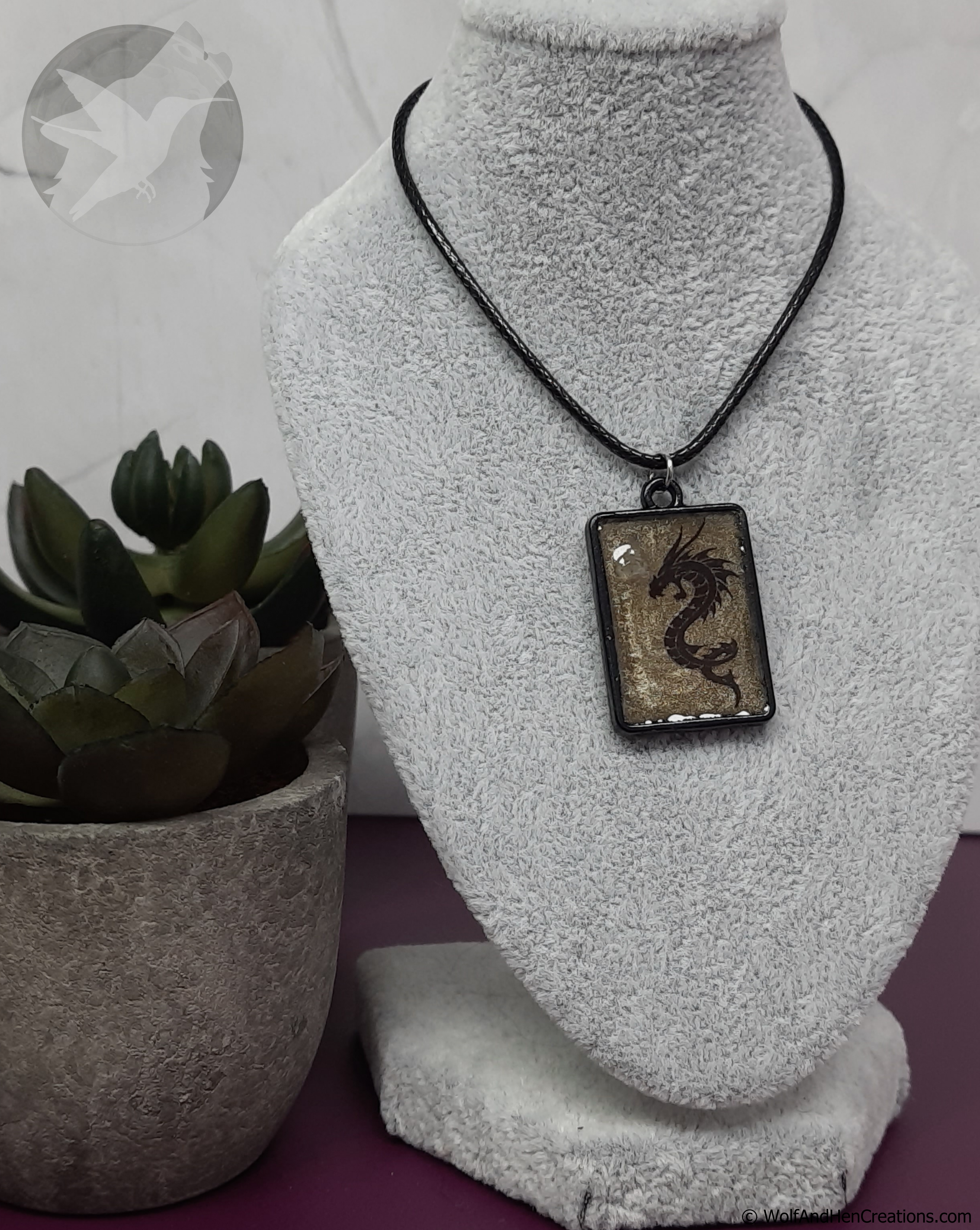 Dragon pendant necklace on a mannequin bust with a plant in the background