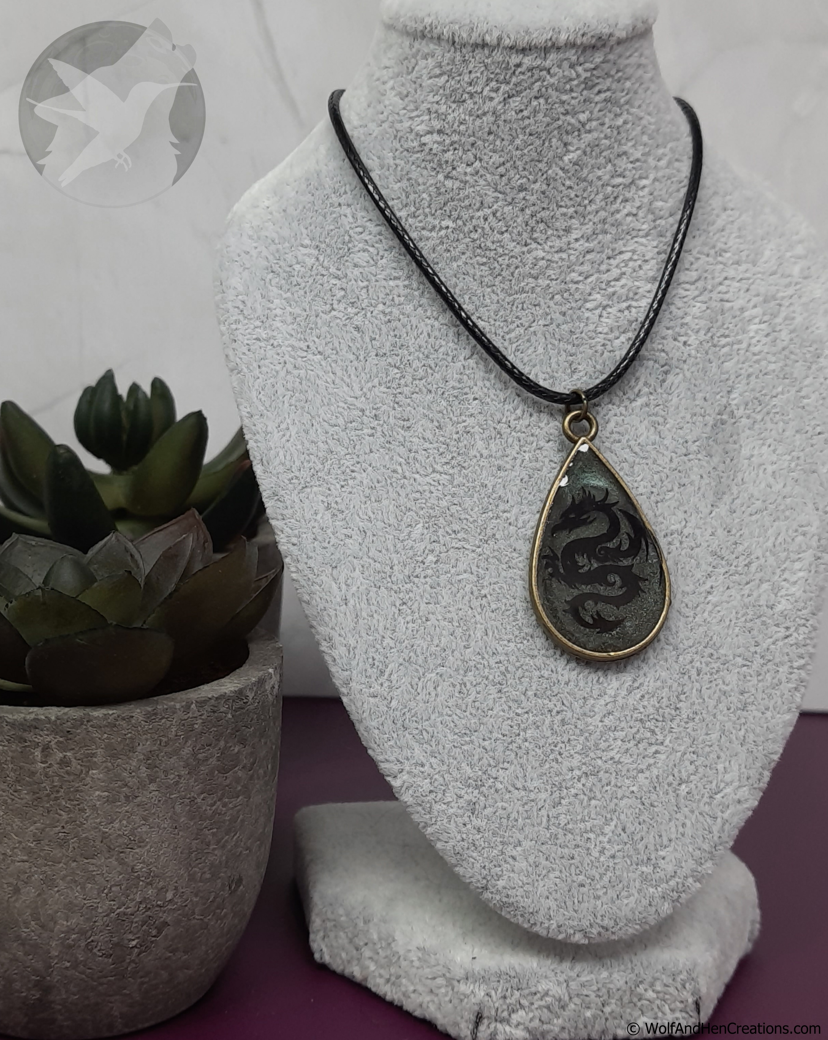 Teardrop-shaped pendant necklace on a mannequin bust with a plant in the background