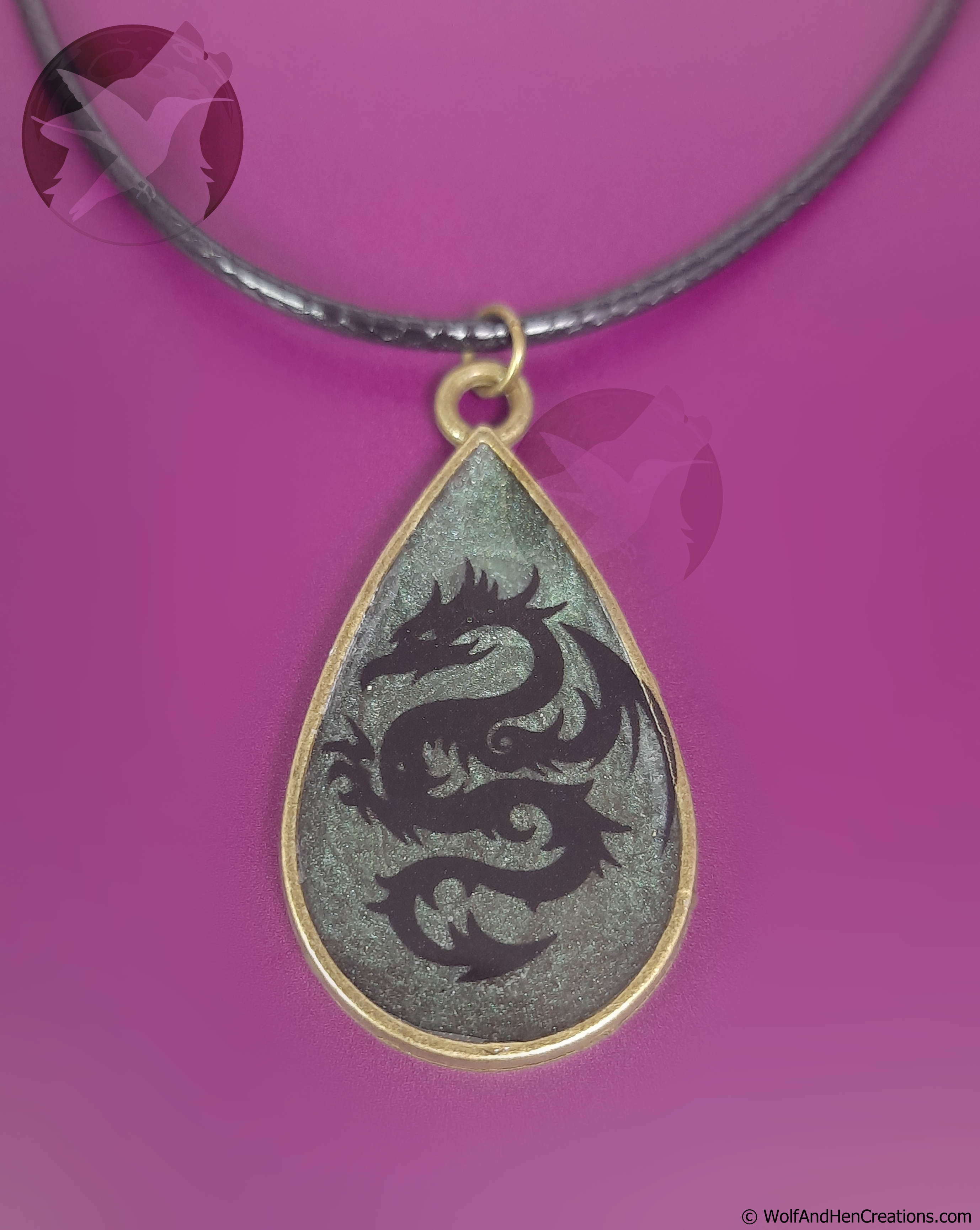 Teardrop-shaped pendant with dragon design on a purple background