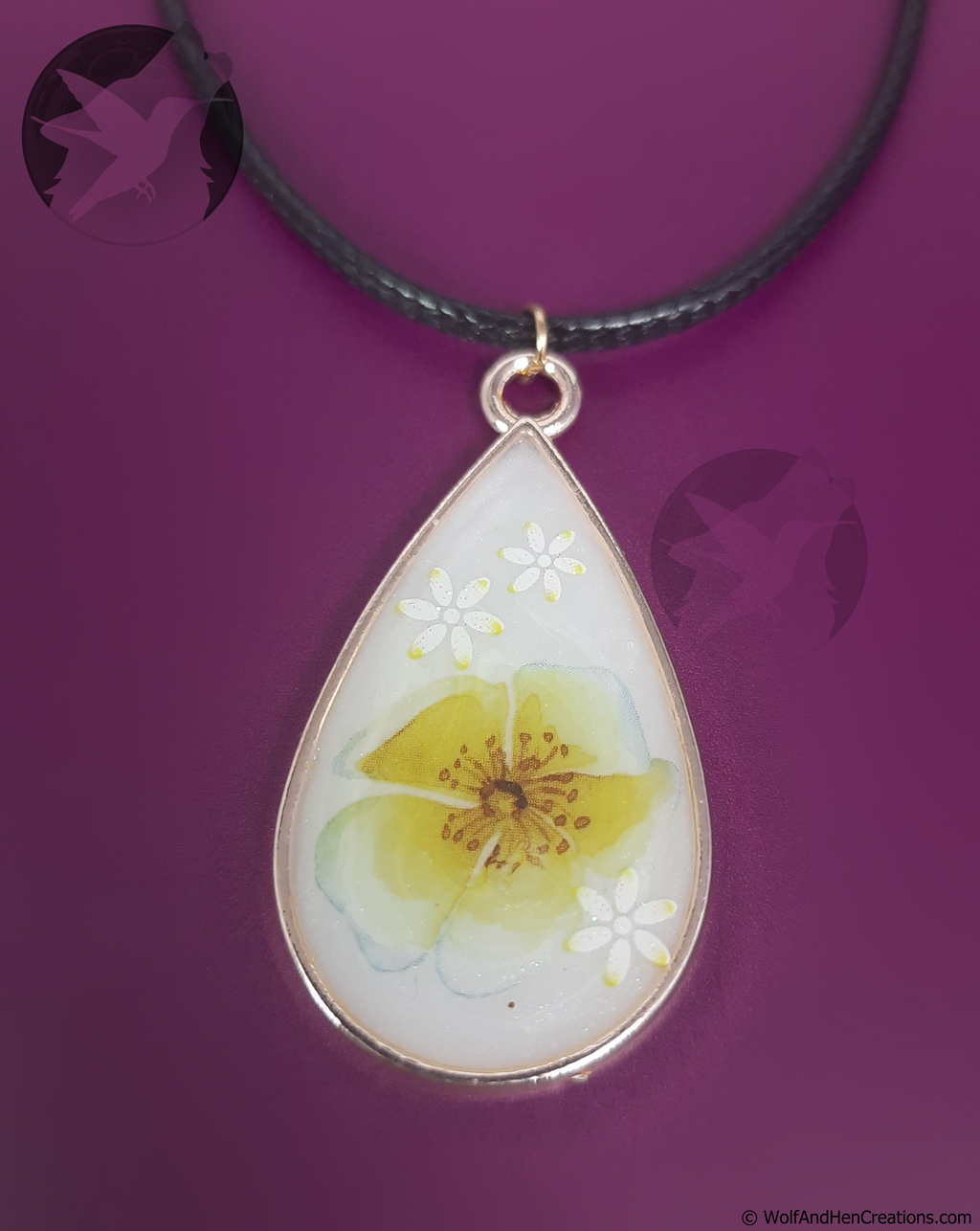 Teardrop-shaped pendant with a yellow flower design on a purple background