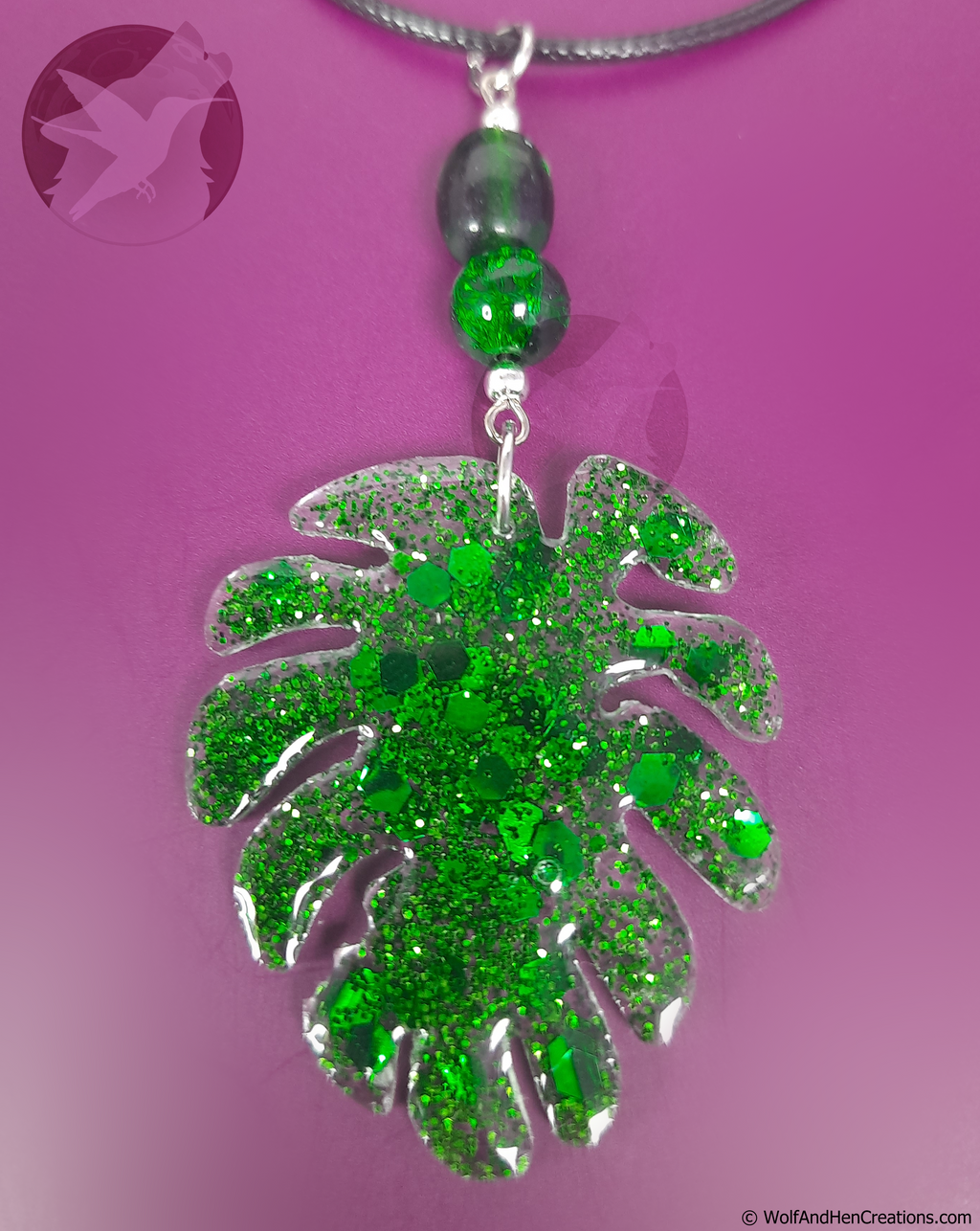 Green glittery leaf-shaped pendant on a purple background