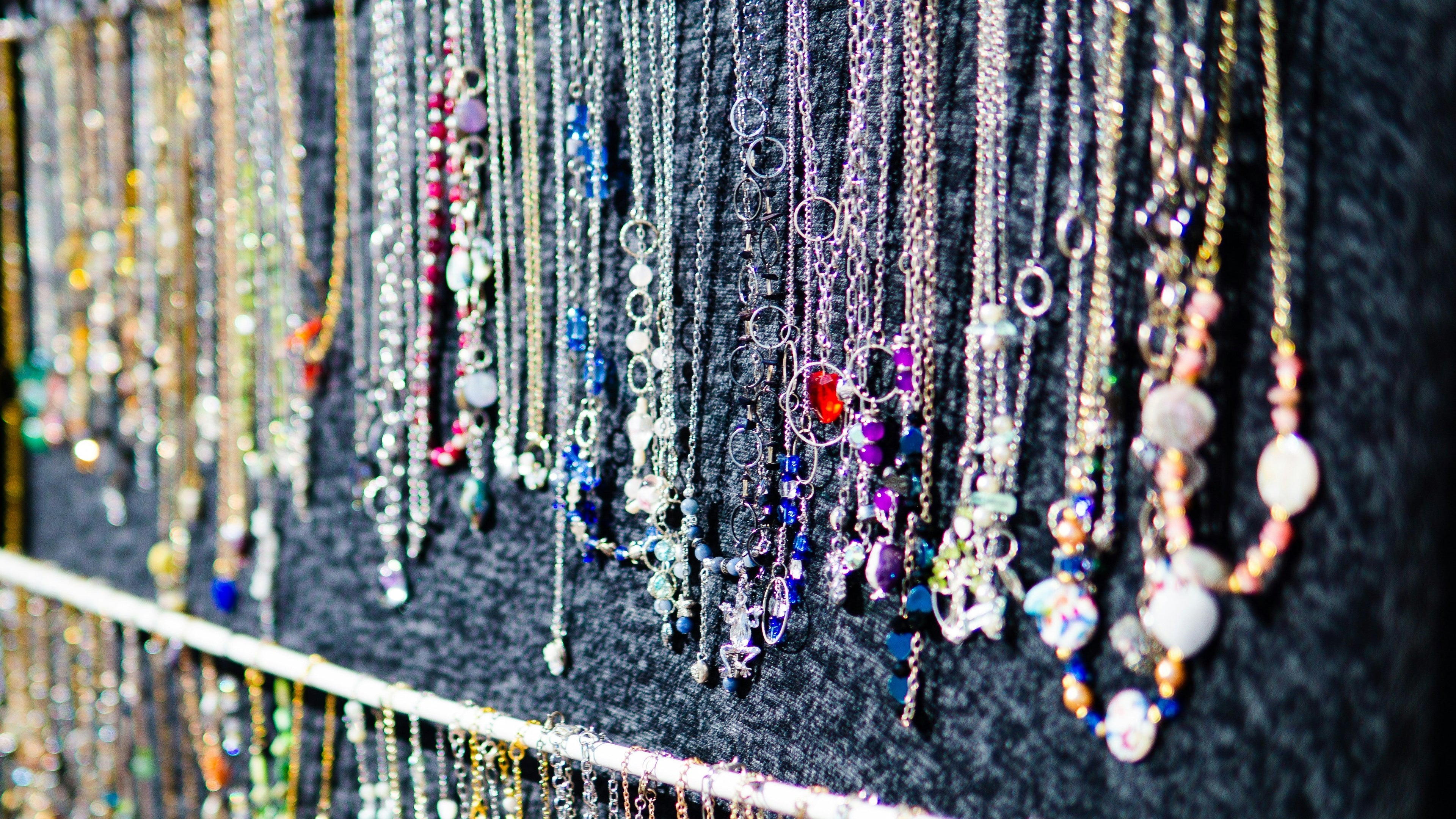 Display of various necklaces on a rack with a black background